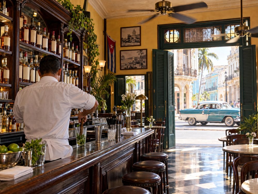 A lively old Havana bar with ceiling fans and a classic car outside