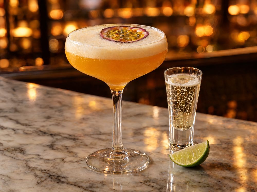 A Pornstar Martini in a coupe with half a passion fruit, a shot of sparkling wine beside it